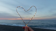 Holding a heart symbol made with bright fairy lights