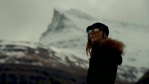 a woman standing in front of a snow covered mountain peak 