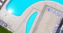Top View Of Outdoor Swimming Pool And Lounge Chairs In A Luxury Resort. aerial drone rotate
