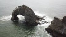 Aerial view over a rock arch in the ocean 