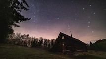 Magic night sky with stars milky way galaxy and clouds motion fast above old wooden hut in wild Carpathian nature Astronomy Time lapse
