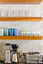 Kitchen wood shelf with appliances blender, coffee maker, toaster, mason jars, cups, glasses, tile back splash