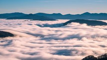 Timelapse of clouds over mountains in nature valley at sunrise.
