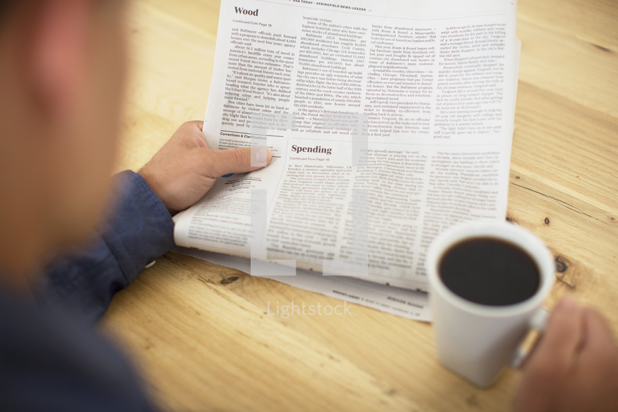 a man reading a newspaper and drinking coffee