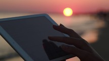 Woman hands typing on pad outdoor at sunset