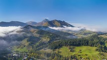 Aerial view of green countryside landscape in autumn mountains with foggy clouds motion in alpine nature Time lapse