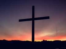 cross silhouette under a purple sky at sunset 