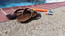 flip flops and dive stick on the edge of a pool 