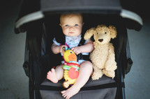 an infant and teddy bear in a stroller 