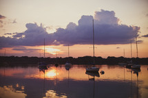 sunset reflected across water and sailboats