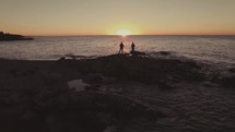 men standing on a beach at sunset 