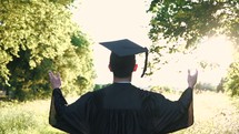 a graduate walking forward and raising hands to praise God and pray