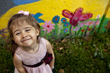 happy little girl standing in front of a painted wall
