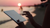 Using touchpad on the beach at sunset