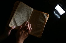 hand on the page of an old Bible