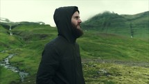man in a hoodie standing outdoors in a valley 