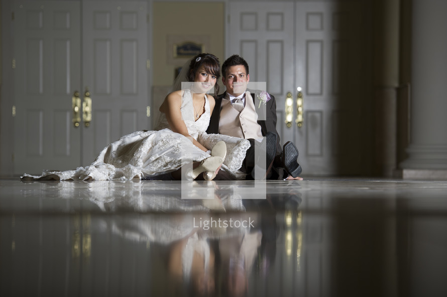 bride and groom sitting on a marble floor