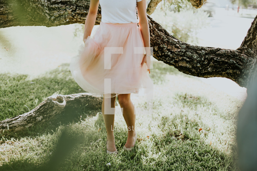 a young woman in a dress walking through a backyard 