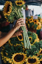 a woman picking out a bouquet of sunflowers 