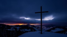 Colorful sunrise over winter countryside nature with religious christian steel cross in top of snowy hill with fast clouds sky Time lapse