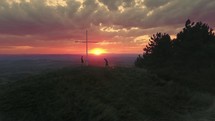 praying by a cross on a mountain top at sunset 