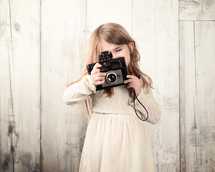 A little girl holding a vintage camera 