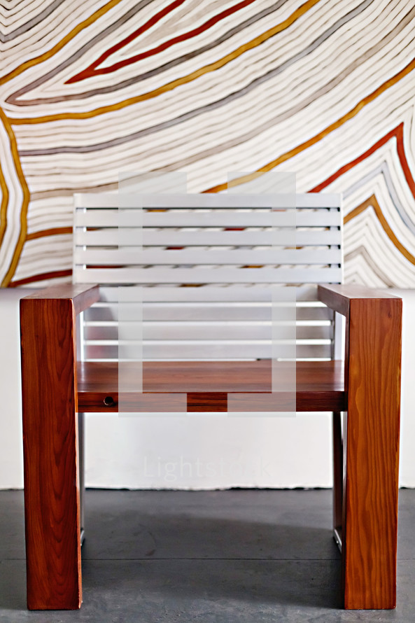 A modern wood chair against a painted striped wall