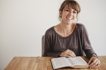 A young woman smiling as she reads her Bible