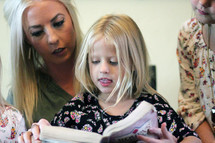 a mother reading a Bible to her daughters 