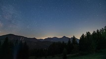 Starry sky with milky way galaxy stars above alpine mountains forest in Morning twilight Time lapse
