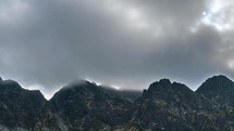 Dark clouds moving fast over rocky alpine mountain peak Time-lapse
