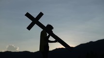 a silhouette of a man with a cross outdoors 