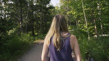 woman walking on a trail through a forest 