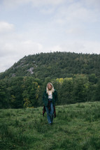 a young woman standing on a green mountaintop 