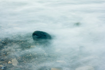 water flowing over rocks on a shore