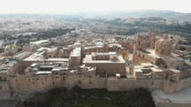 Mdina, the silent city, view outside city walls overlooking the cityscape limestone buildings in Malta - Ascending panoramic aerial shot 
