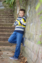 Young boy standing and posing against a old stone wall
