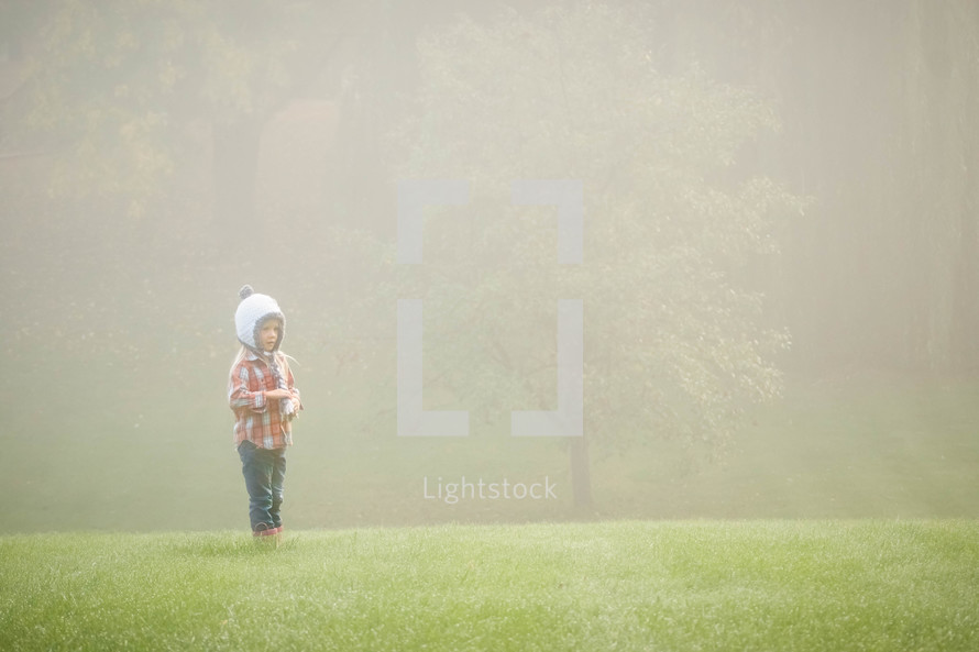 a girl standing outdoors in the fog 