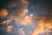 a plane in the sky flying through pink clouds 
