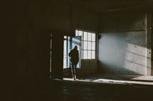 a man standing at a window in an abandoned warehouse 