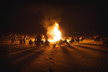 people sitting around a beach bonfire 