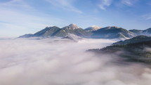 Timelapse of misty morning clouds in alpine mountains.
