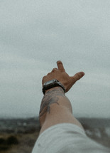 Man's arm with tattoo pointing toward sky