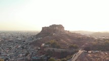 Mehrangarh Fort contrasting with golden sunset at the foothill of the border of Jodhpur, Rajasthan, India - Aerial wide Panoramic shot