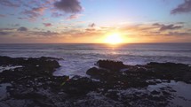 Colorful sunset over ocean coast with slow motion waves in summer evening in New Zealand
