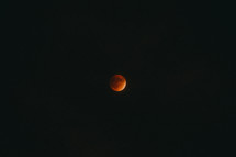 A red moon in a black night sky.