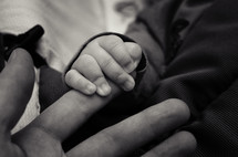 infant holding man's fingers 