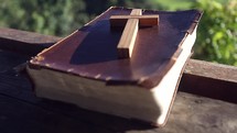 cross and Bible on a railing outdoors 