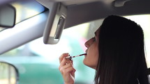 a woman putting on makeup in a car 