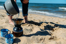 woman brewing coffee on a beach 